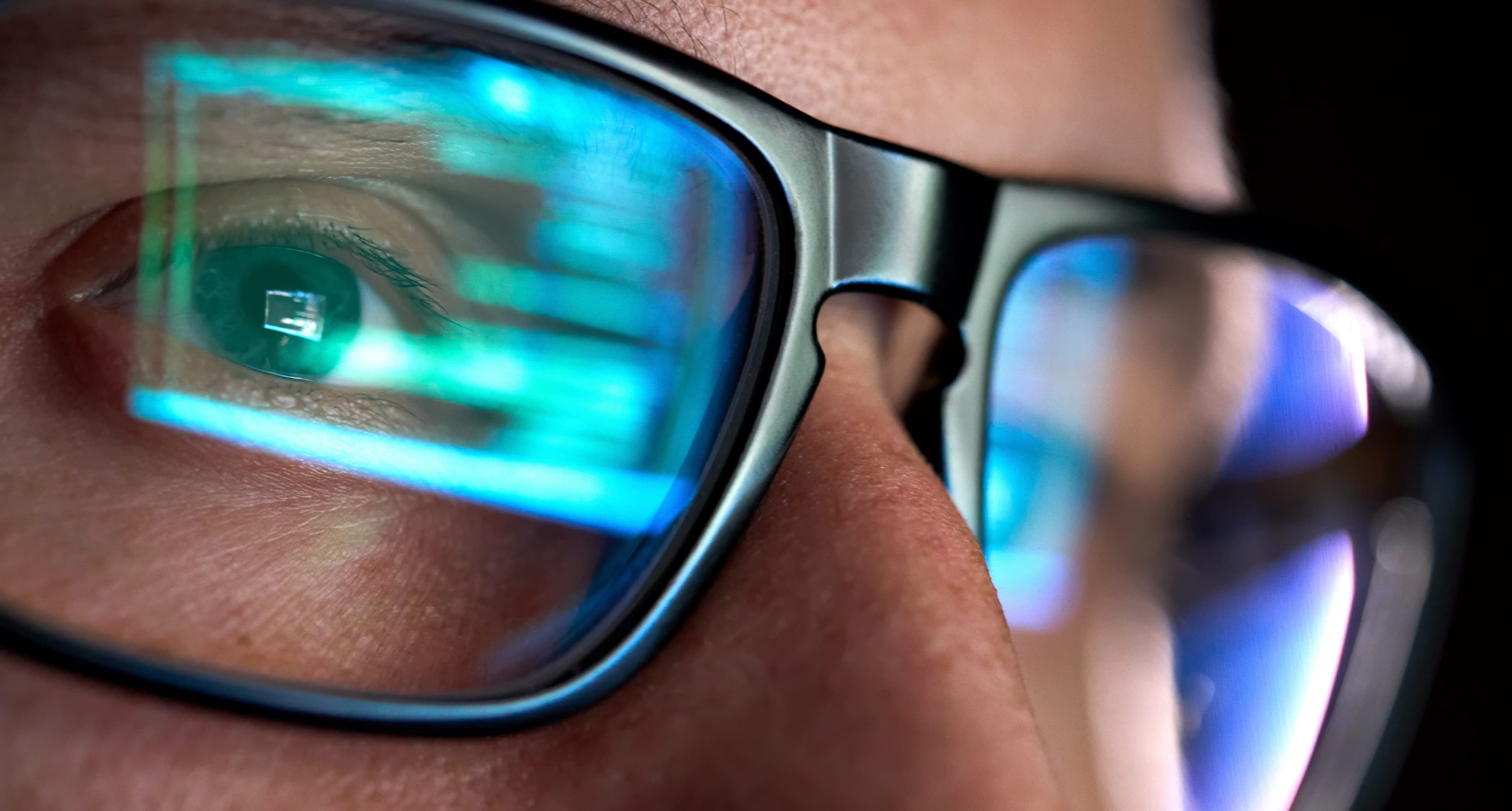 Close-up of an engineer’s glasses reflecting monitoring screens