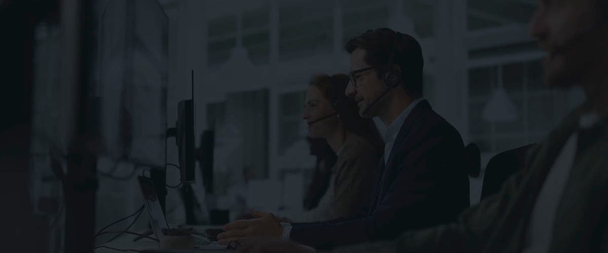 Call center agents wearing headsets and working at a row of desks