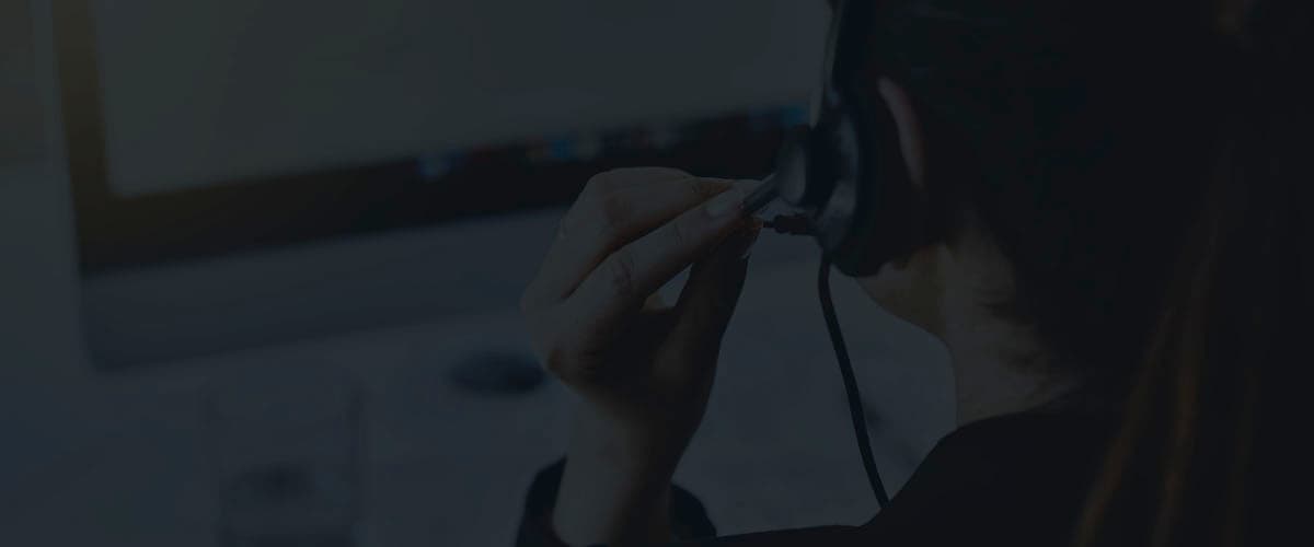 Call center agent adjusting a headset while seated at a computer