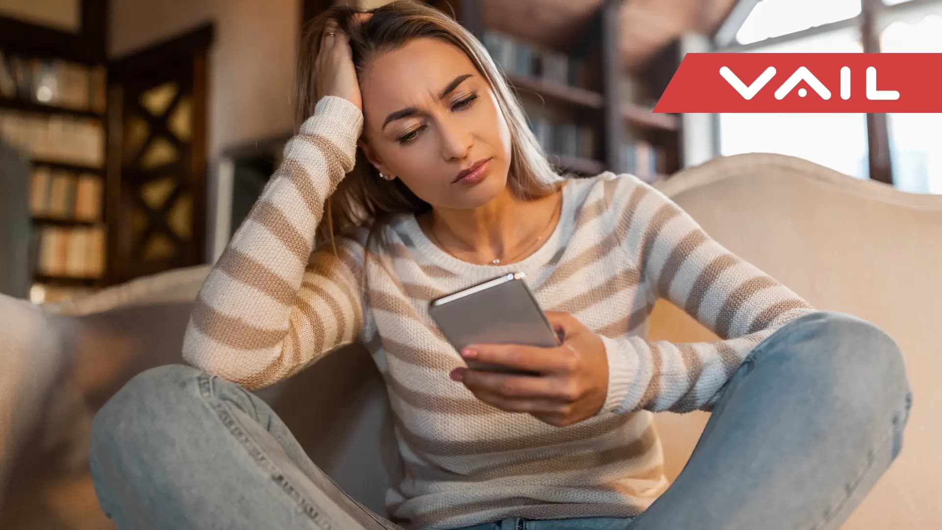 Women sits looking at her phone with frustration